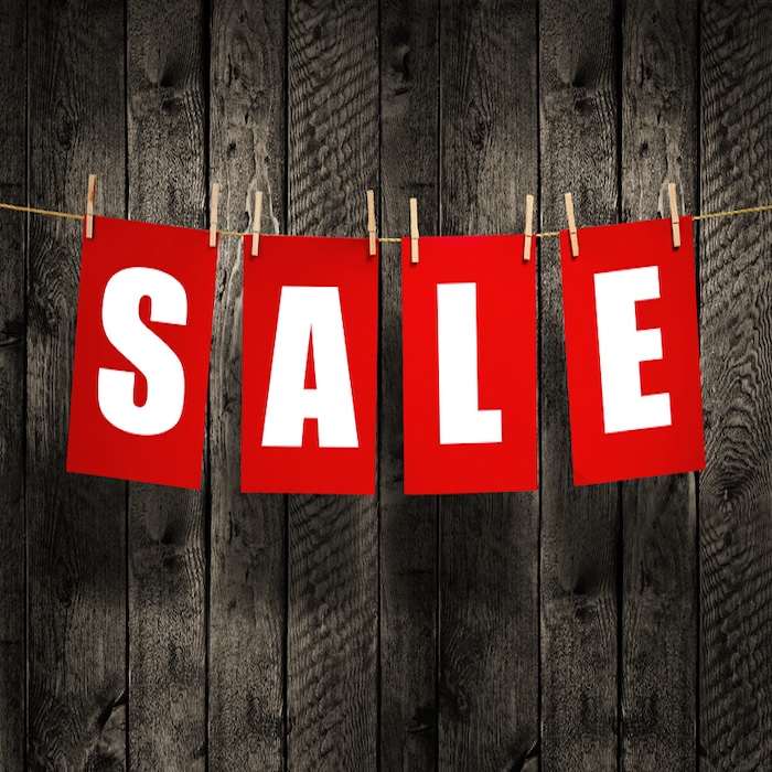 While on red letters spelling SALE on wood background