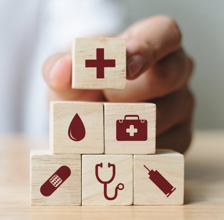 Hand stacking blocks with medical icons.