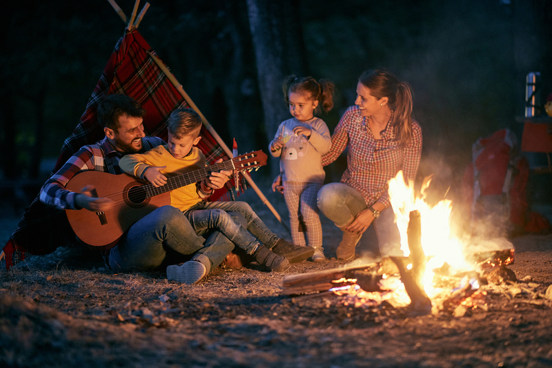 Family of five by tent and campfire.
